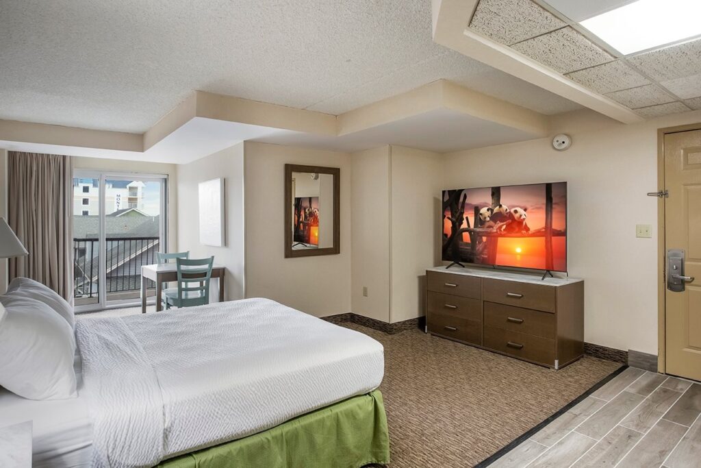 a hotel room with a bed, dresser and television