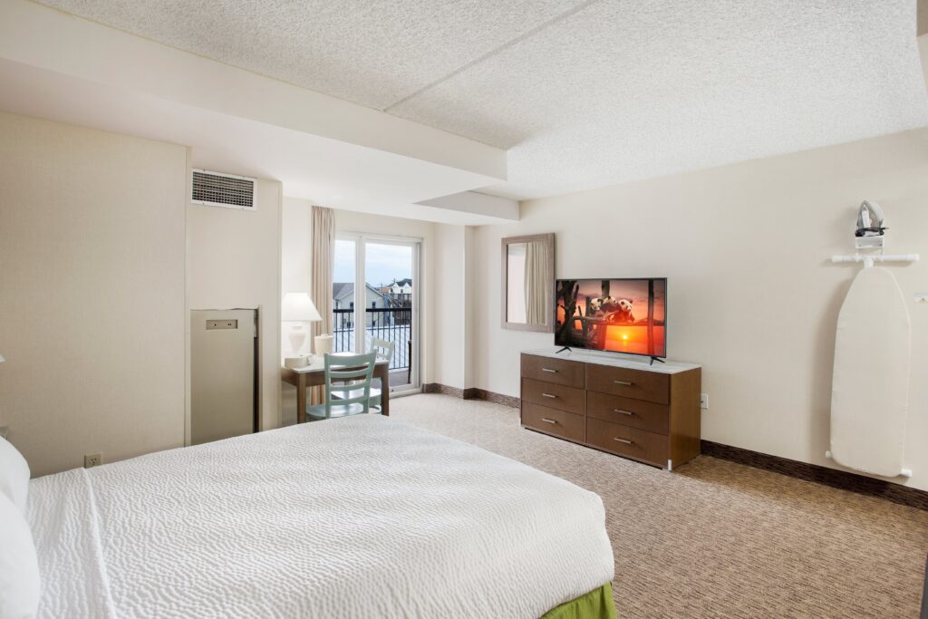 a hotel room with a bed, dresser and television