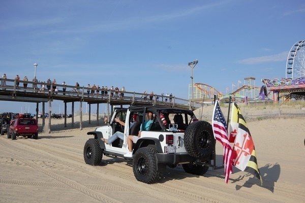 a group of people riding on top of a white jeep