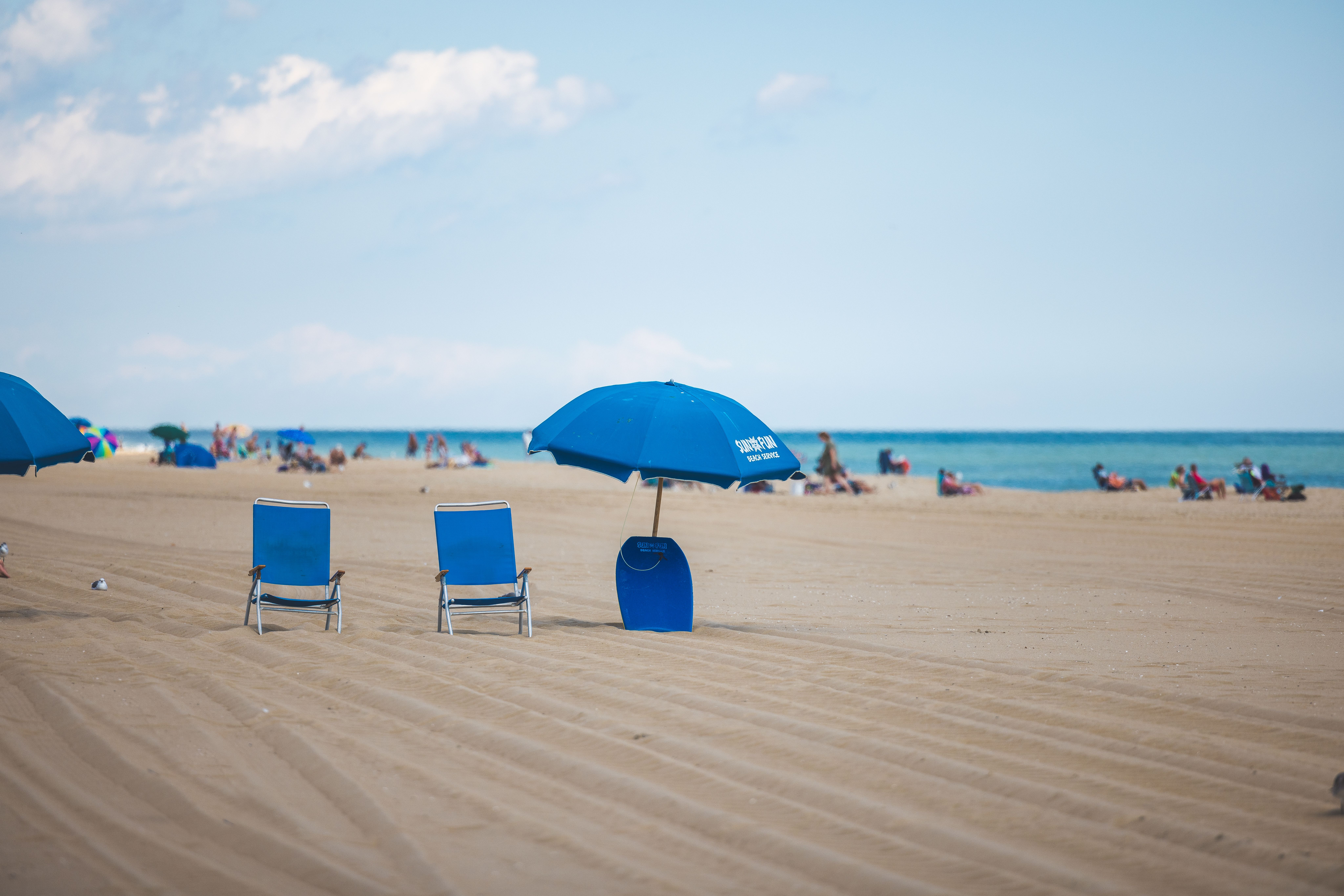 chairs and umbrellas on the beach with people in the background