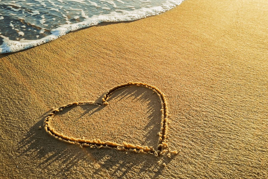 a heart drawn in the sand at the beach