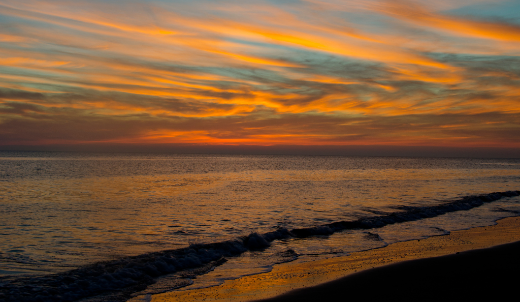 a sunset over the ocean with clouds in the sky