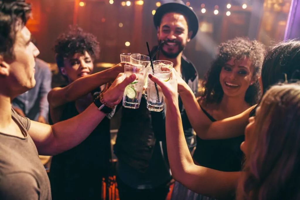 a group of people standing around each other holding glasses