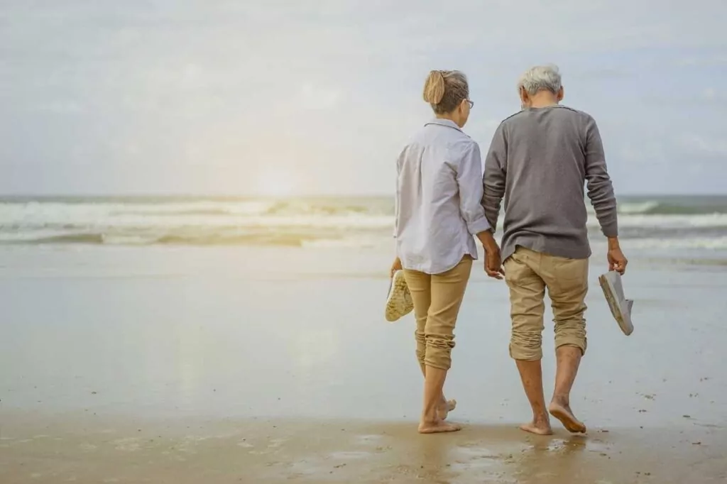 an older couple walking on the beach holding hands