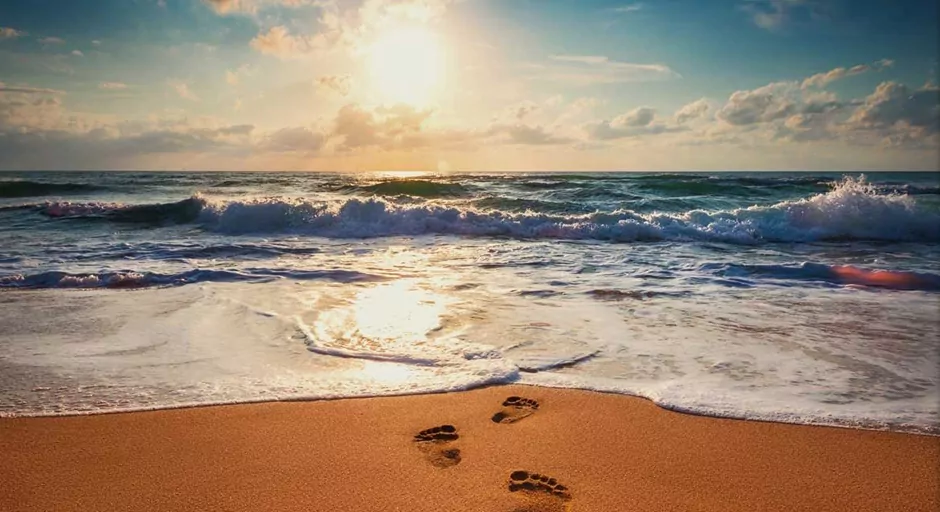 footprints in the sand on a beach with waves